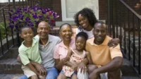 Image of a multi-generational African American family sitting on a front step of a home
