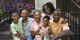 Image of a multi-generational African American family sitting on a front step of a home
