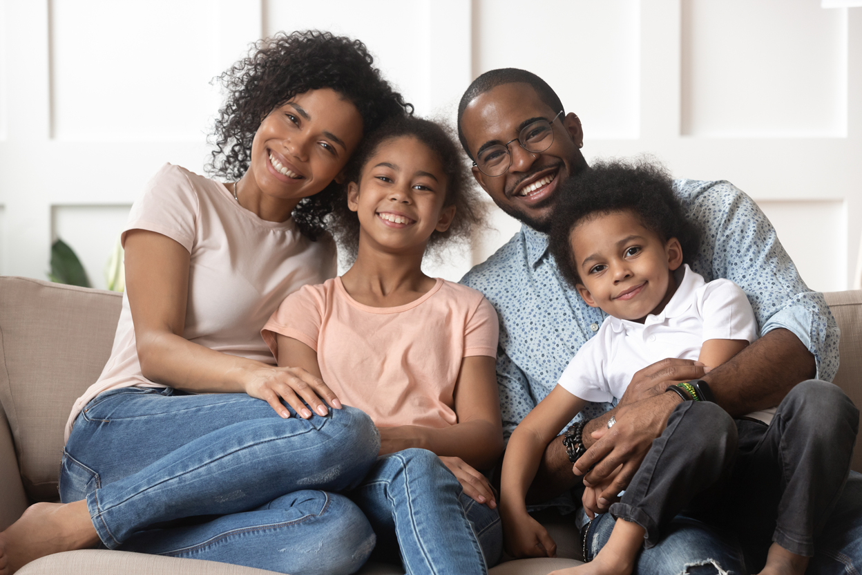 African American family sitting on thee couch taking a photo together